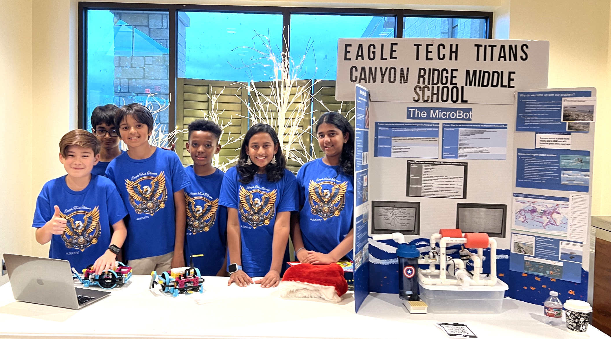 The EagleTechTitans displaying their 'MicroBot' with informational boards about plastics in the ocean and the technological challenge.